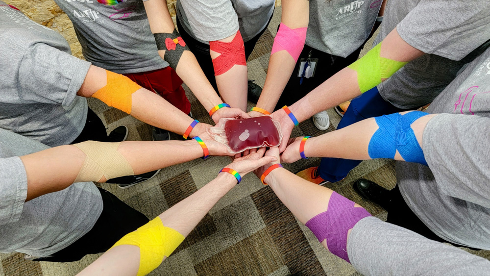 a group of people's arms after donatging with rainbow bandages